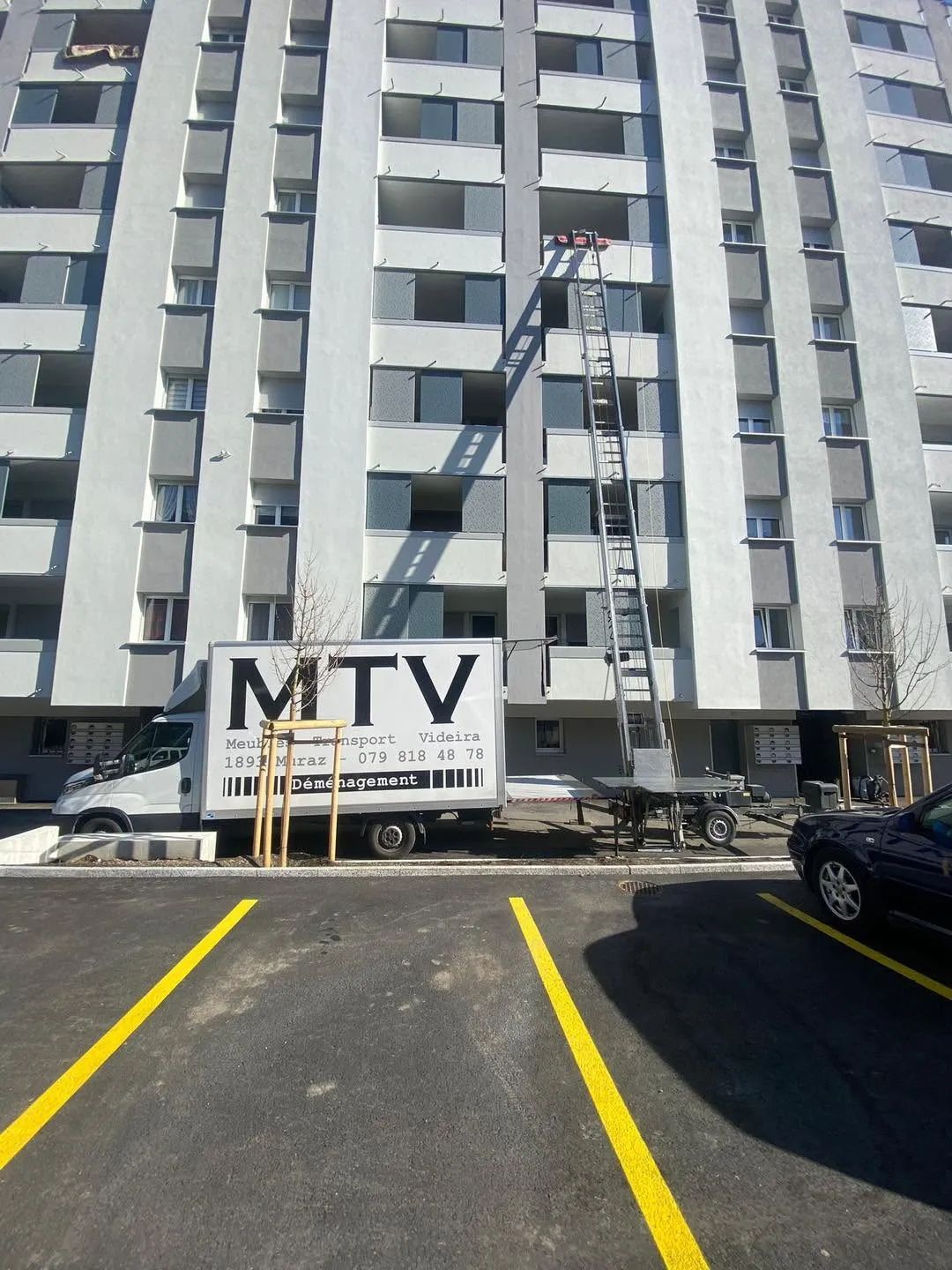Camion MTV avec monte-meuble déployé jusqu'aux étages hauts d'un immeuble en Valais